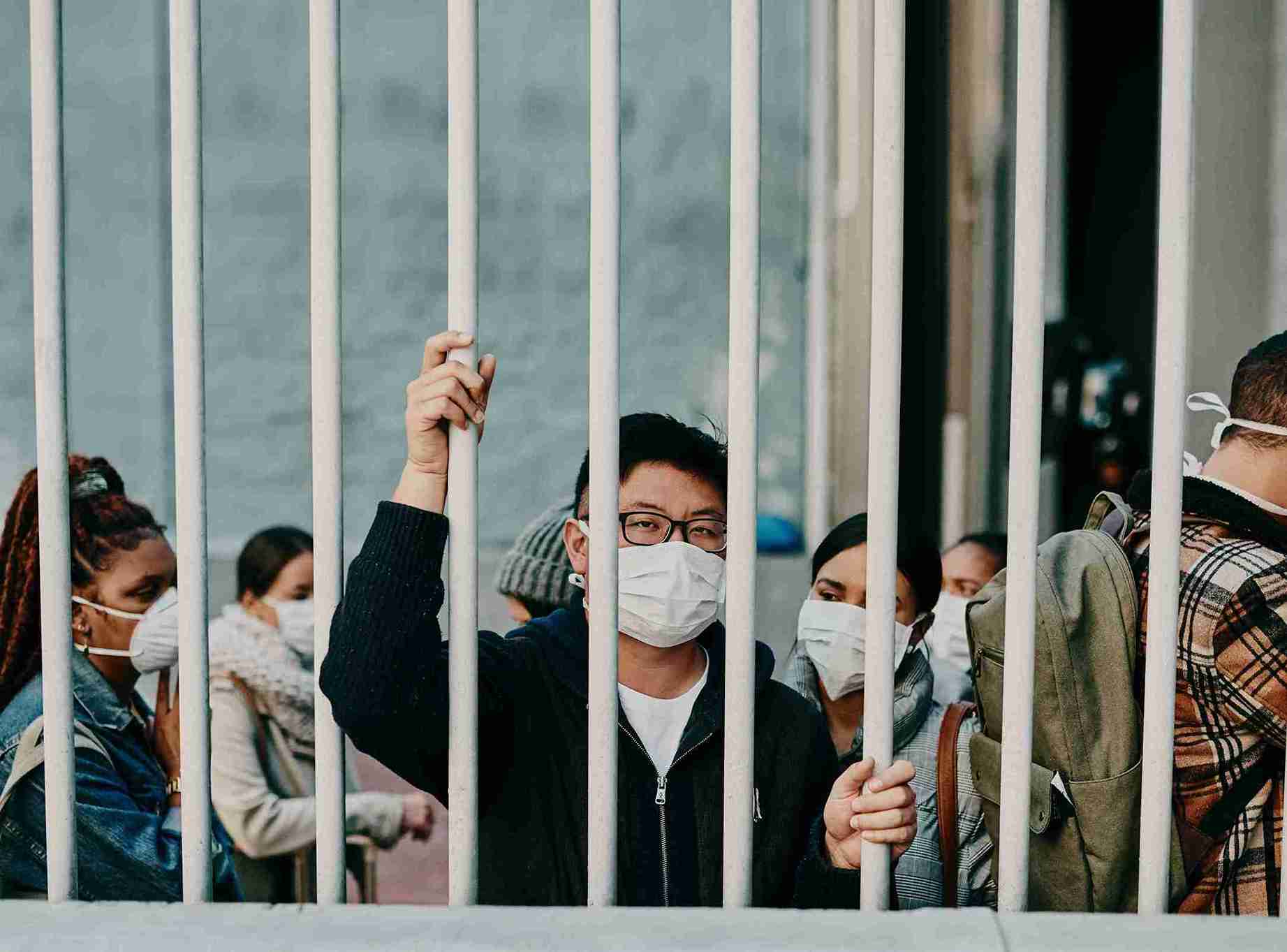 A man behind bars wearing masks detained and are being deported.