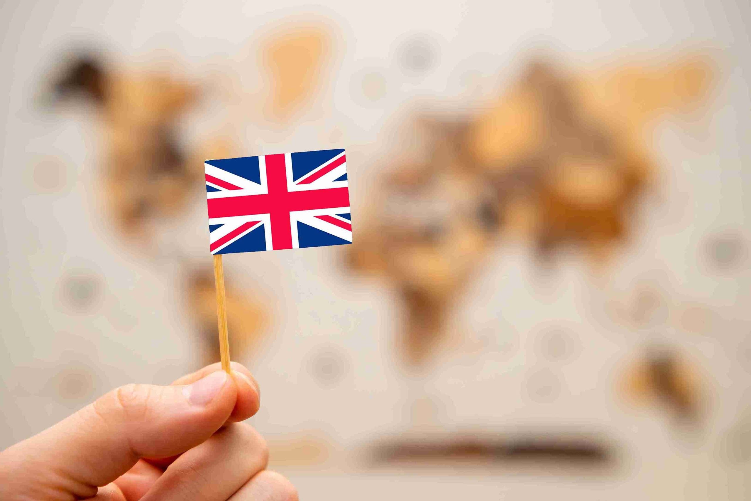 Hand holding flag of UK on map defining route to UK.
