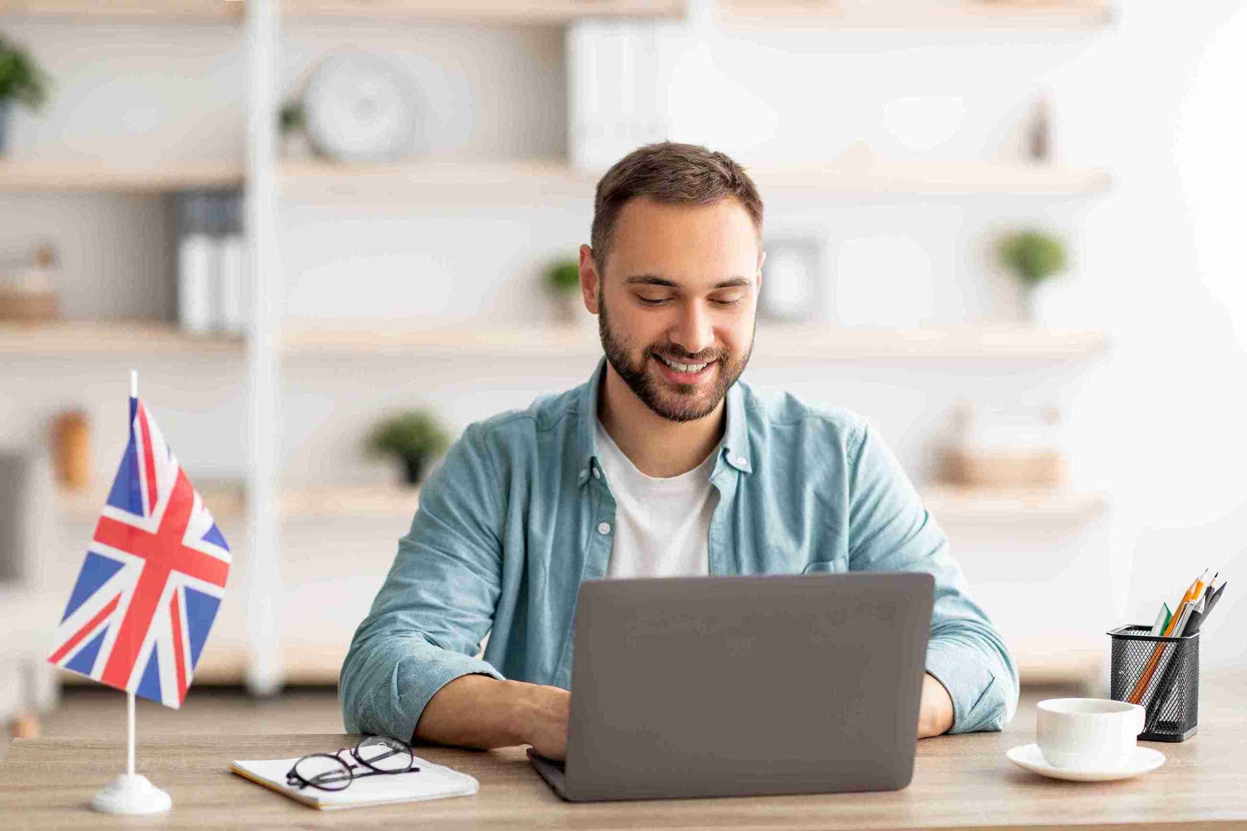 A man smiling while using laptop at desk.