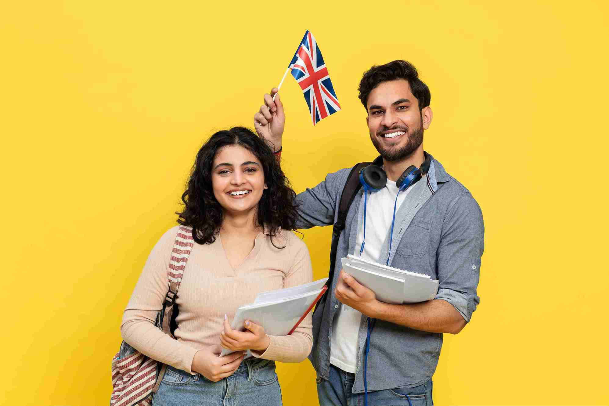 Smiling young adults holding books and British flag.