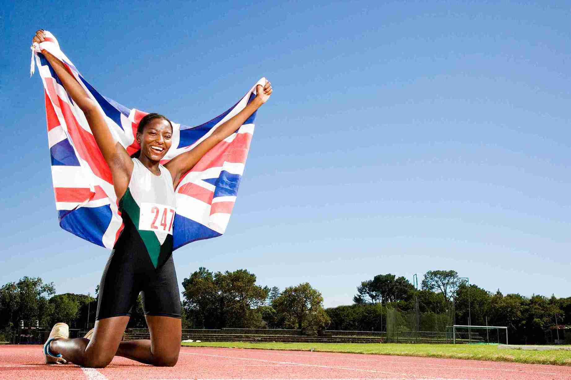 Women celebrating with flag on running track.