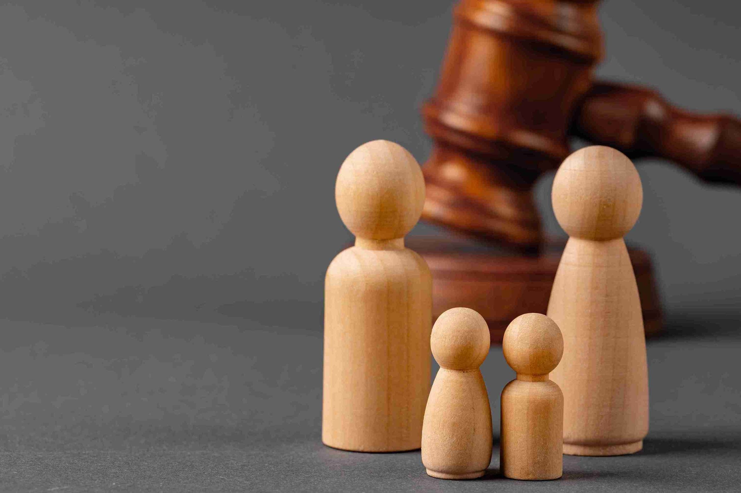 Wooden family with gavel on back illustrating family law and justice.