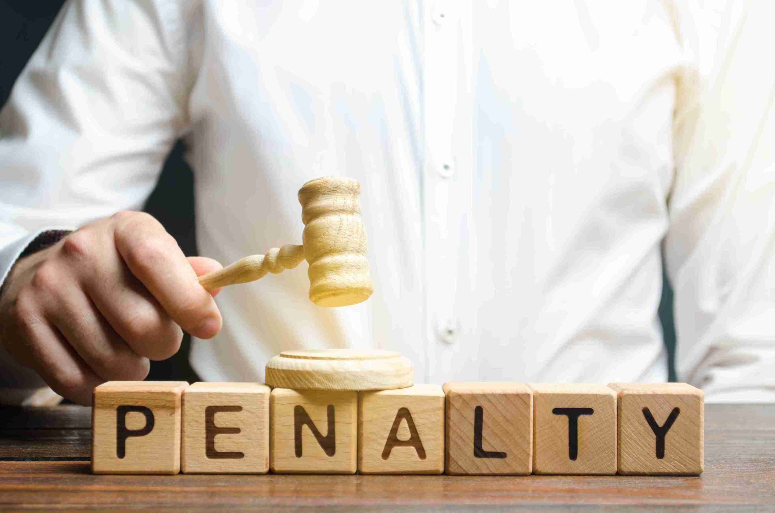 A person with gavel beneath penalty written on wooden blocks.